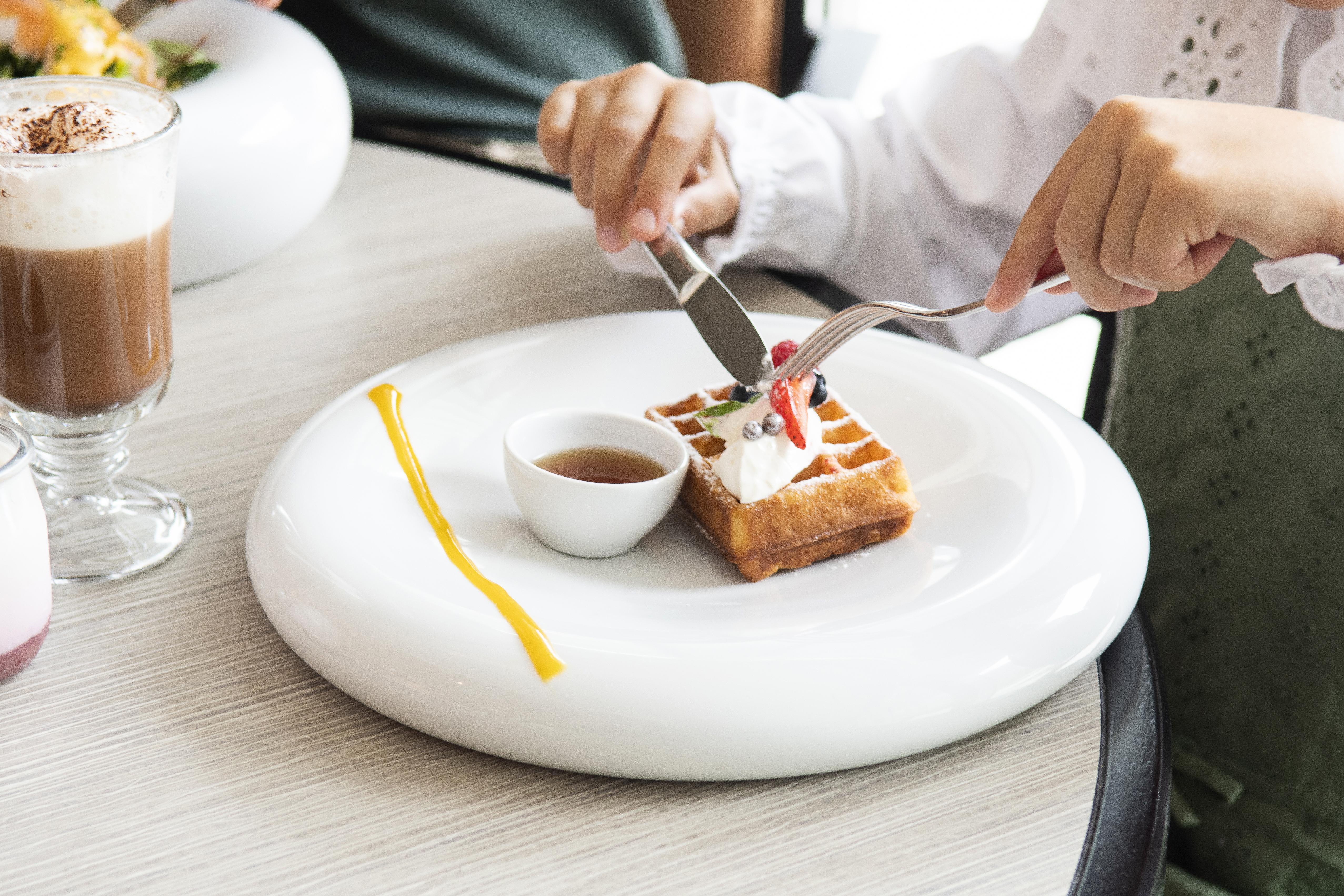 Epic Sana Lisboa Hotel Bagian luar foto A woman using a knife and fork to cut a dessert